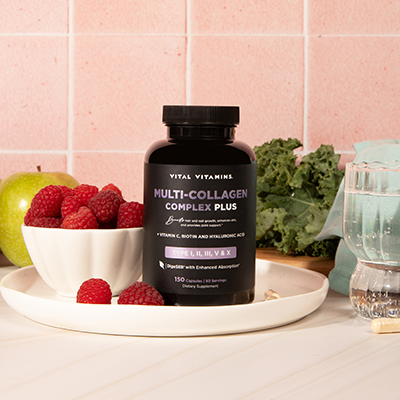 Vital Vitamins Multi-Collagen Complex Plus bottle on a kitchen counter with raspberries, an apple and a wooden cutting board