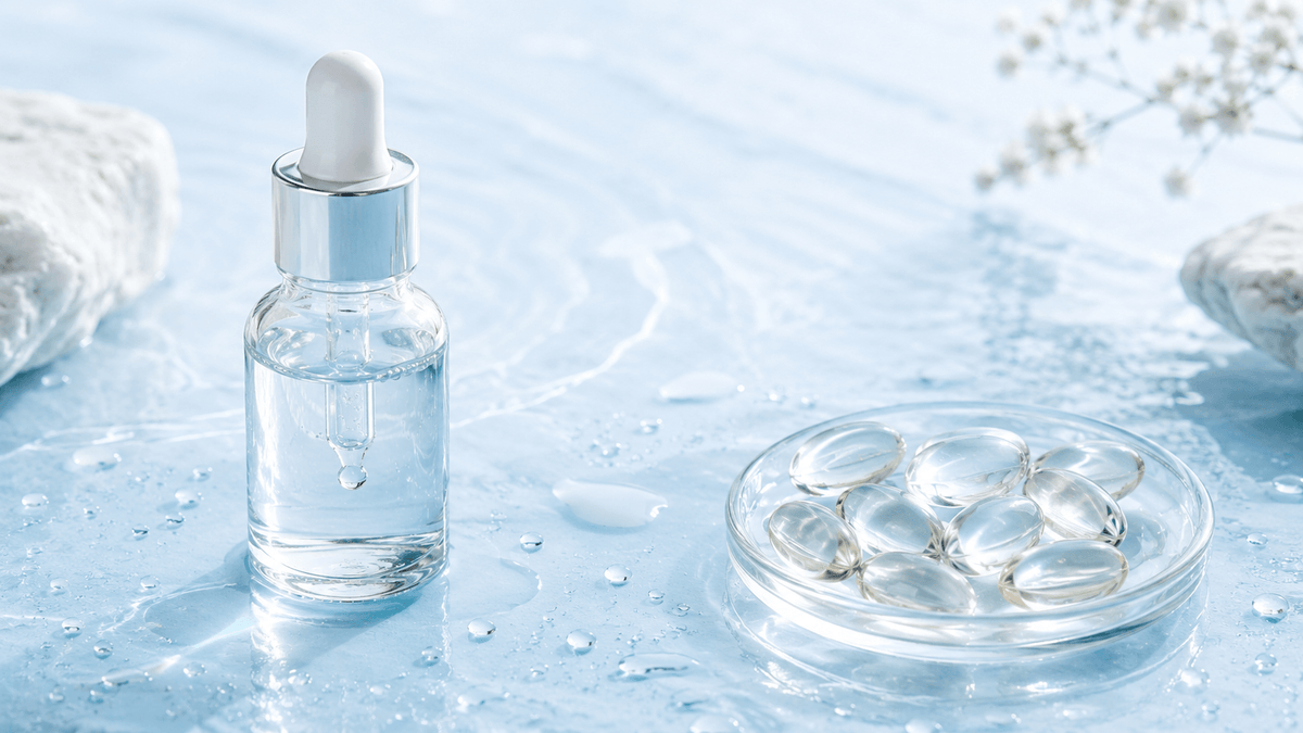 Serum dropper bottle next to a dish of soft-gel capsules with water droplets, comparing topical and oral hyaluronic acid