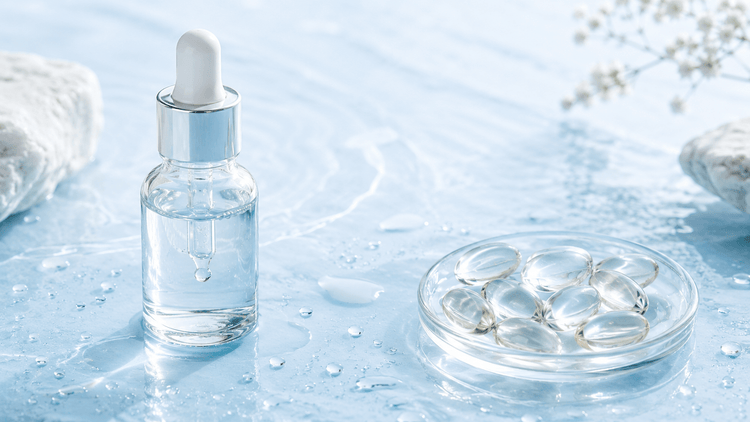 Serum dropper bottle next to a dish of soft-gel capsules with water droplets, comparing topical and oral hyaluronic acid