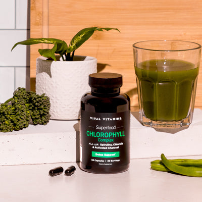 Vital Vitamins Chlorophyll Complex bottle on counter beside a houseplant and glass of green juice - daily detox supplement